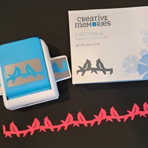 Black surface with a card featuring a creative memories cardinals stamp and a box with a design on it